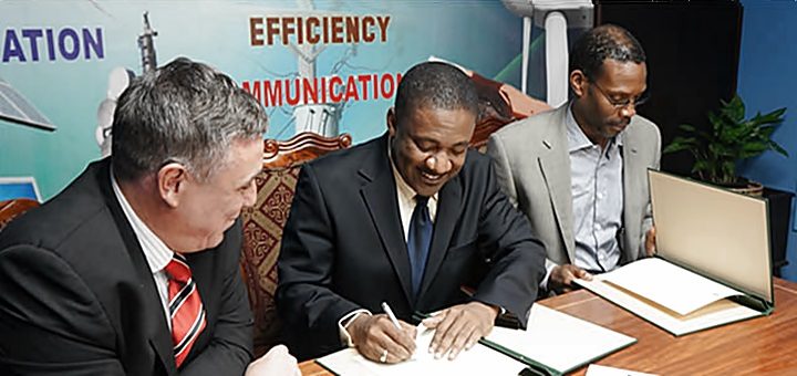 Phillip Paulwell, ministro de Ciencia, Tecnología, Energía y Minería firma el acuerdo para la renovación de la licencia de Digicel, rodeado por Barry O'Brien, CEO de Digicel izquierda) y Garfield Sinclair, CEO de Lime (derecha). Imagen: MSTEM.